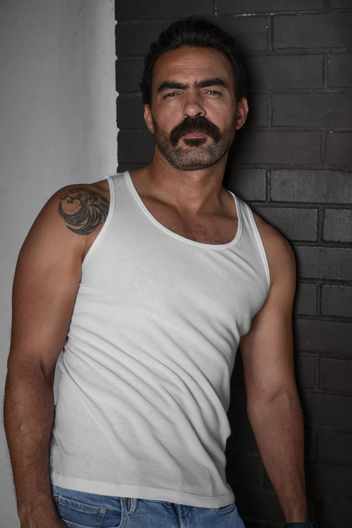 Actor Ali in a white tank top against a brick wall for a Vancouver character headshot