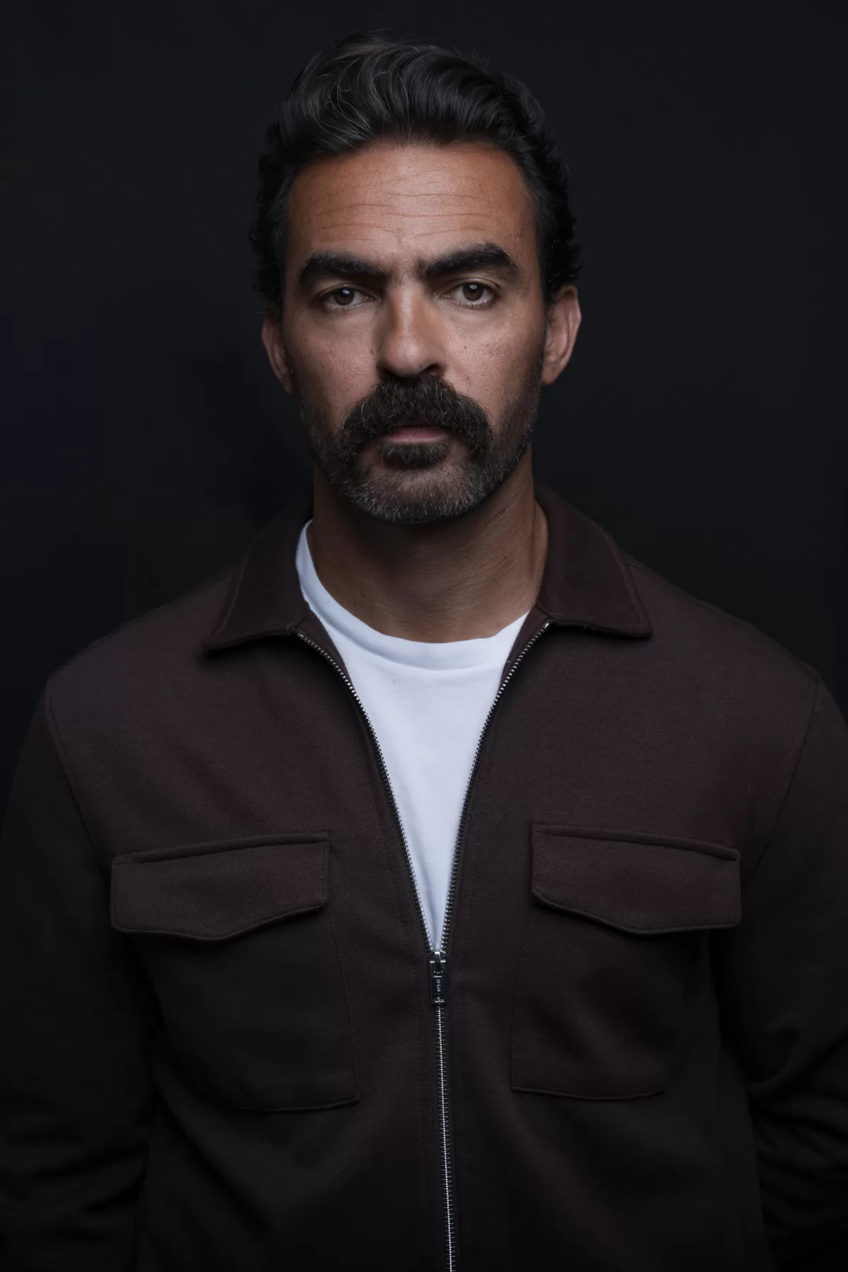 Dramatic studio actor headshot of Ali with a dark jacket and direct expression