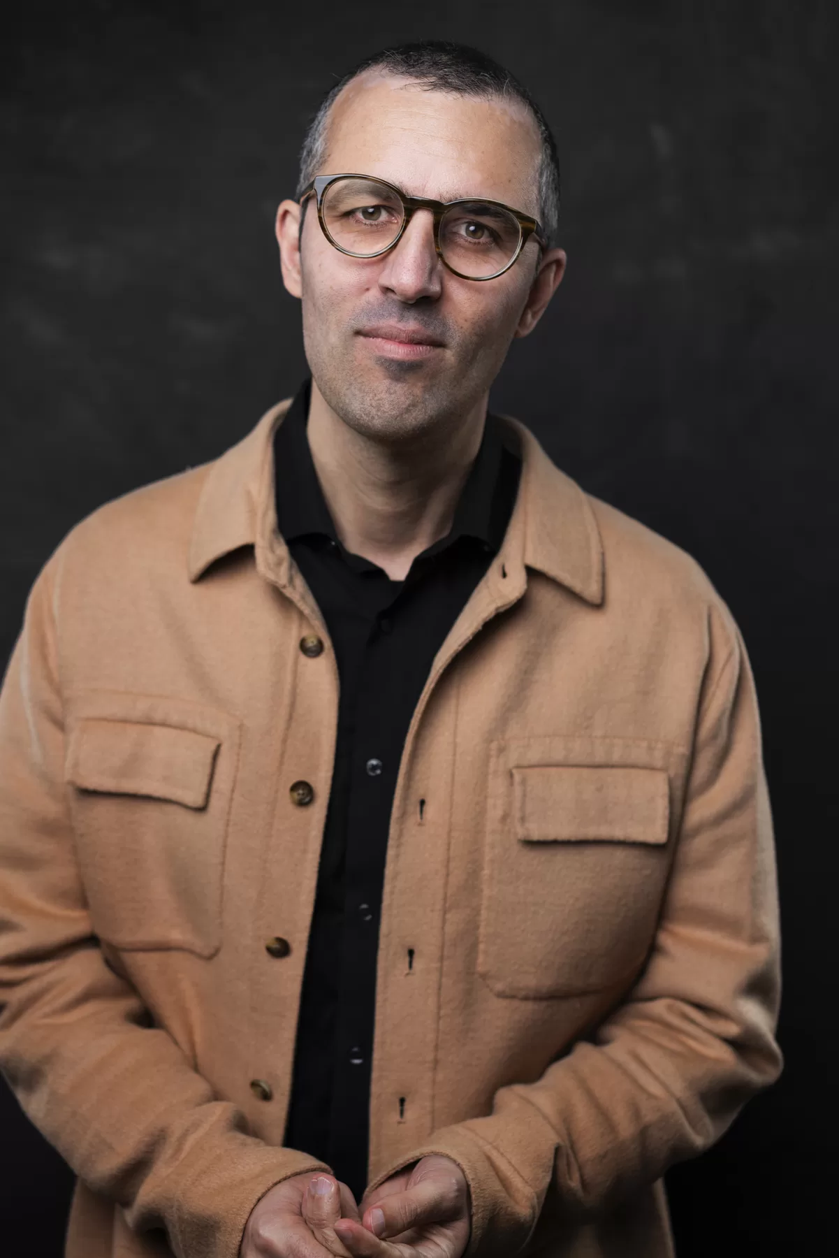 Commercial actor portrait of Sam K wearing glasses and a tan jacket
