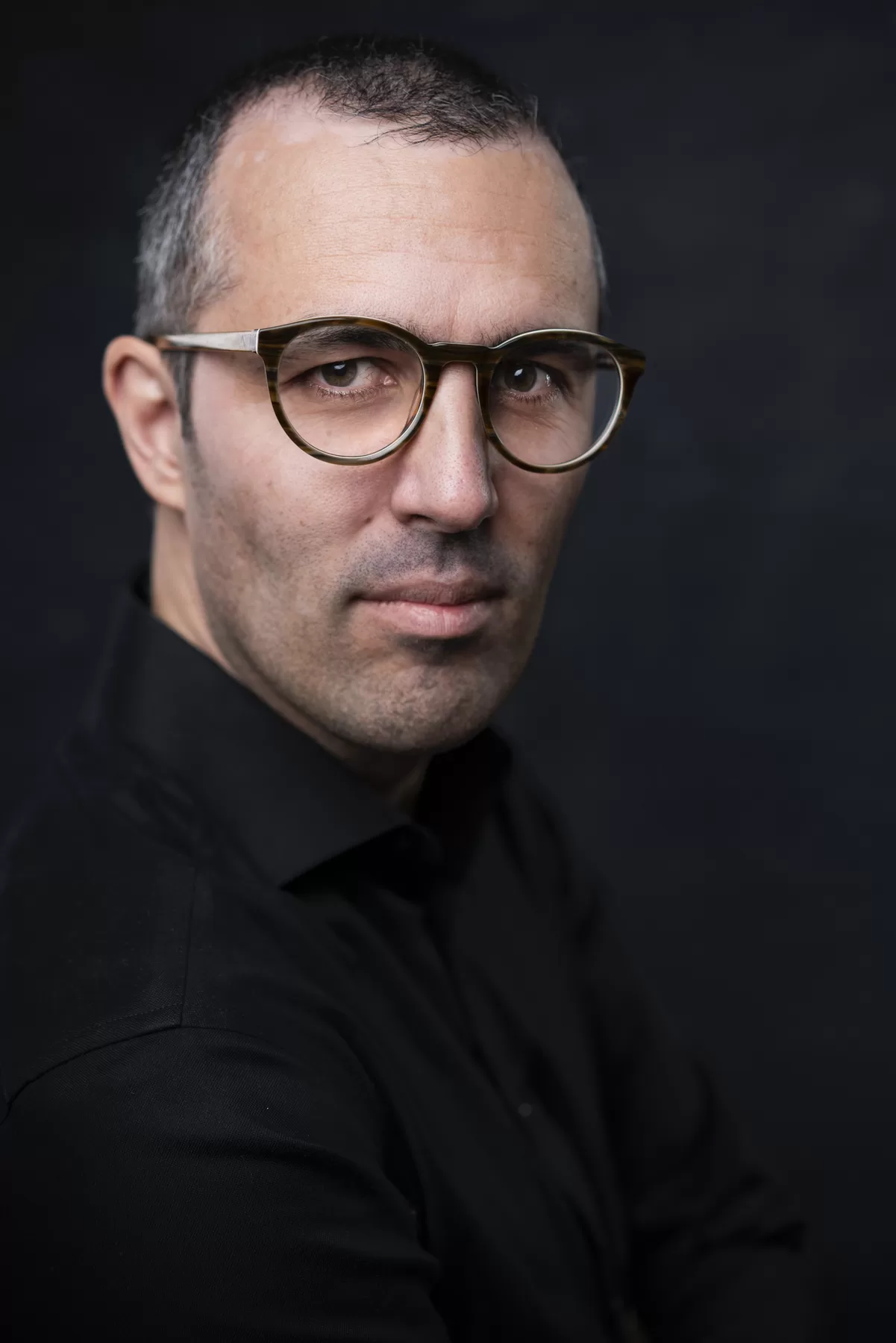 Dramatic Vancouver actor headshot of Sam K wearing glasses and a black turtleneck