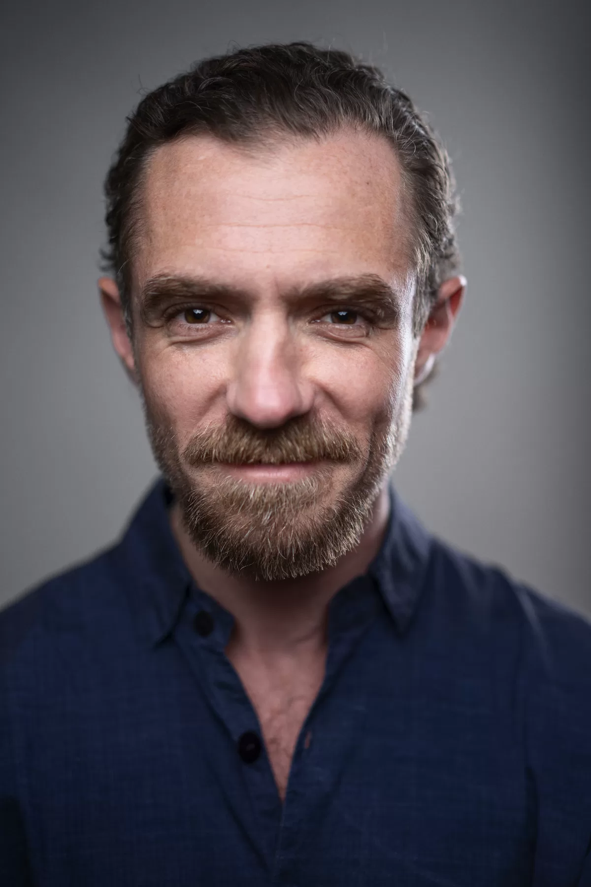 Friendly actor headshot of William smiling in a blue shirt