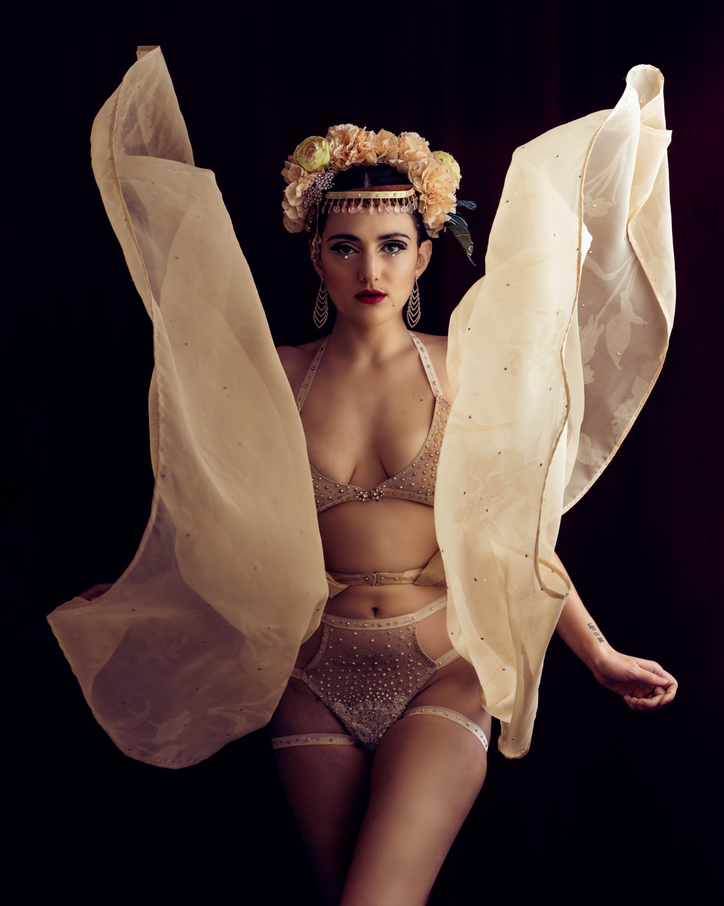 Promotional portrait of burlesque performer Delta Daggers posing with flowing costume fans