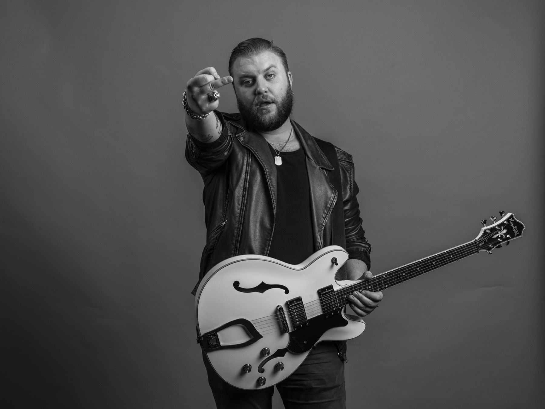 Black and white band promotional portrait of Mannerfors with a white guitar