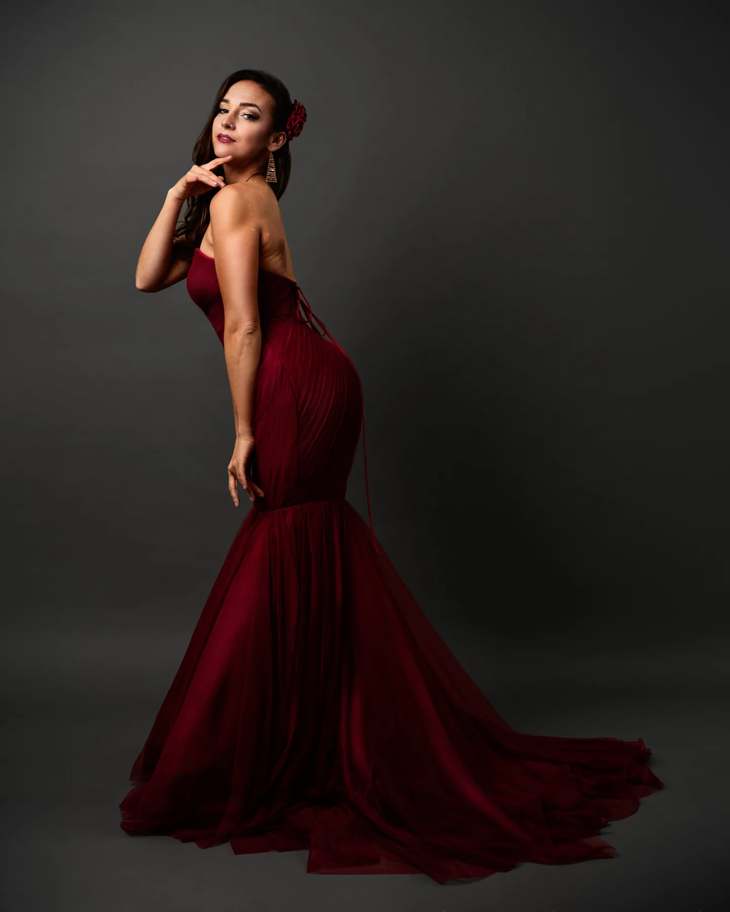 Full-length fashion portrait of a woman wearing a sculptural red gown