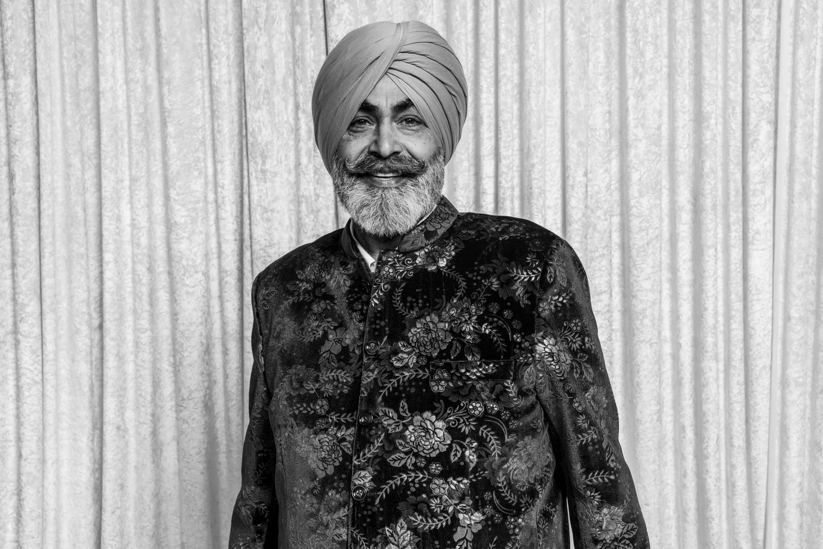 Smiling guest wearing a patterned jacket and turban