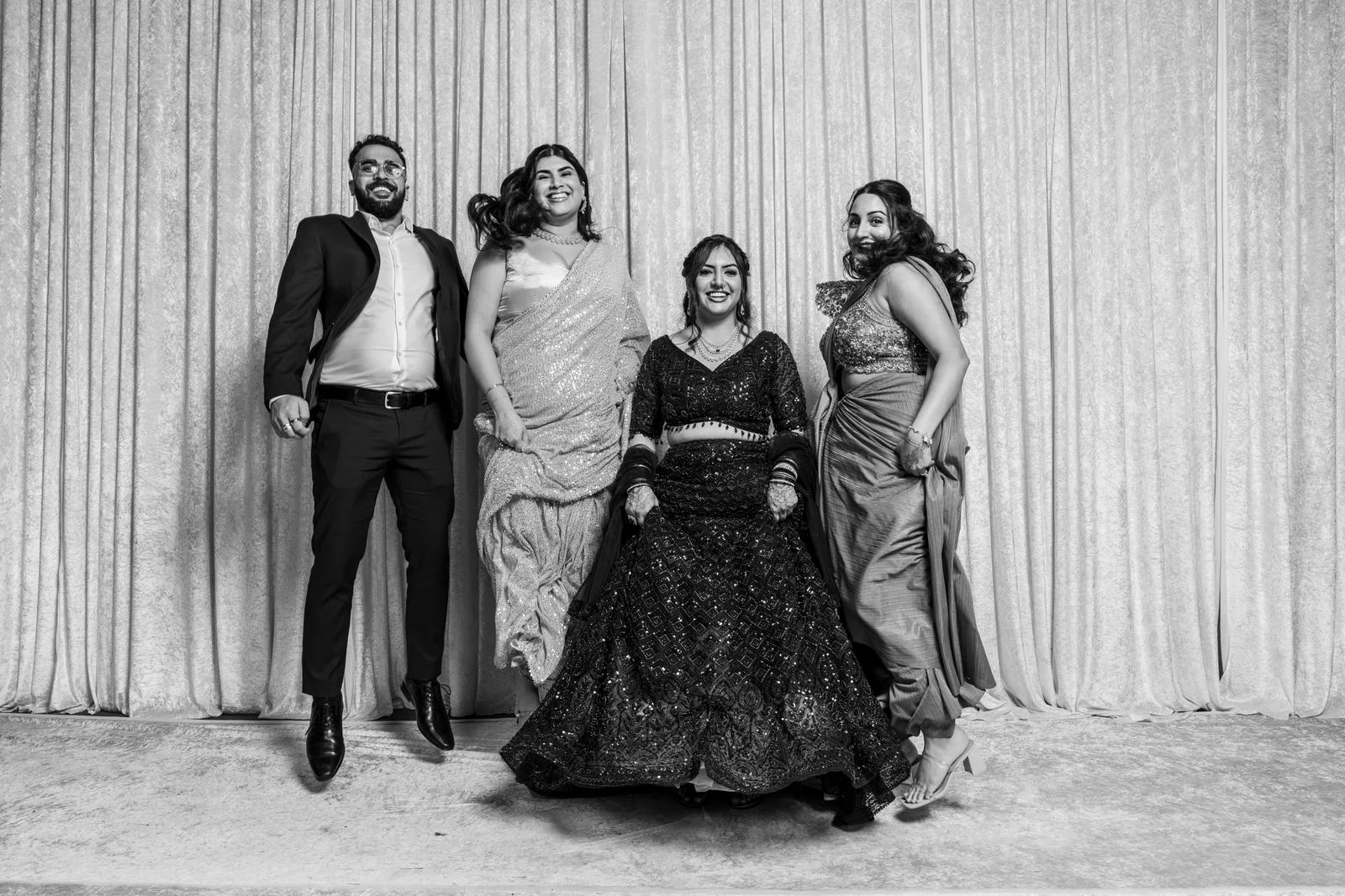 Wedding guests laughing and jumping together in the event portrait studio
