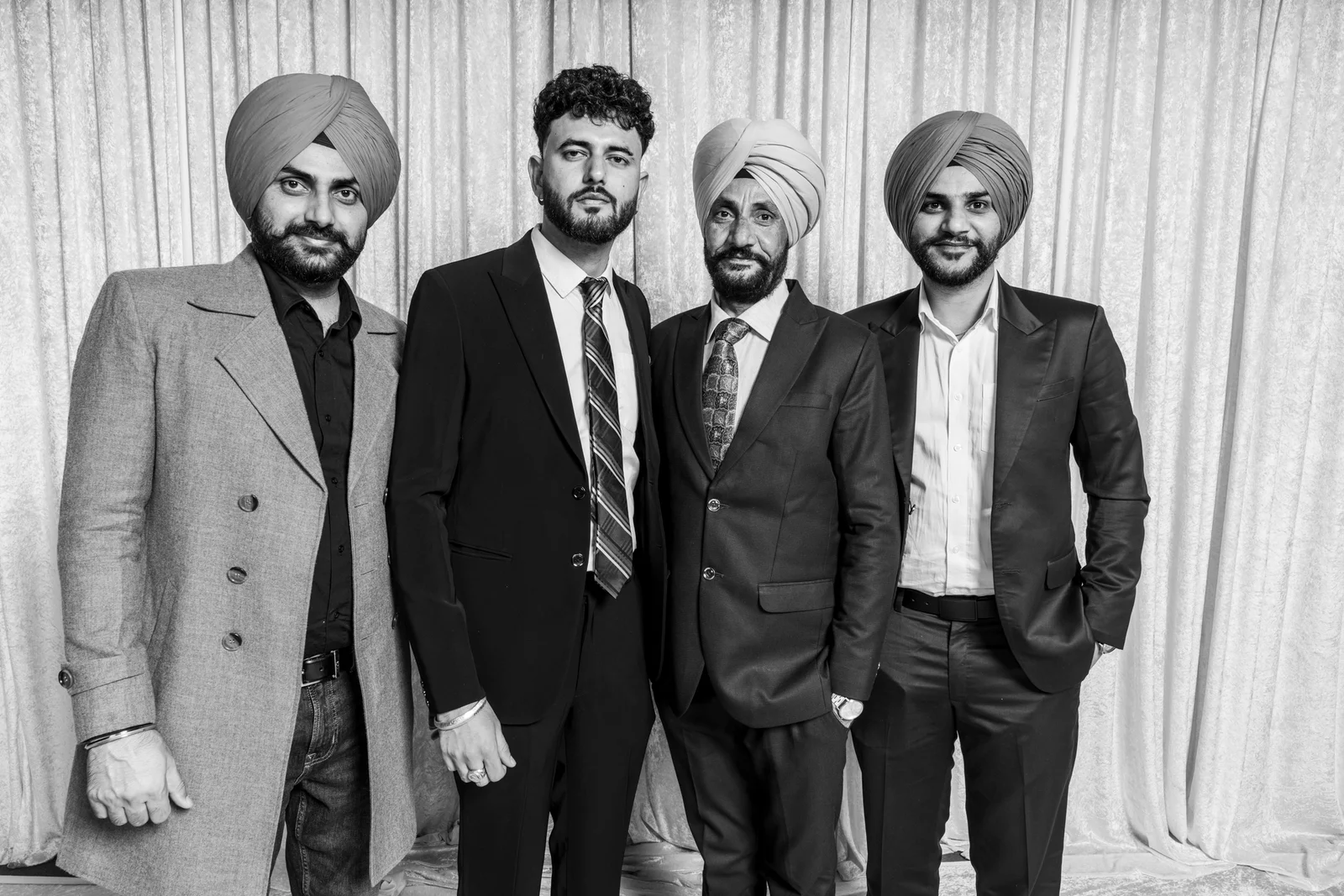 Four wedding guests posing together in suits