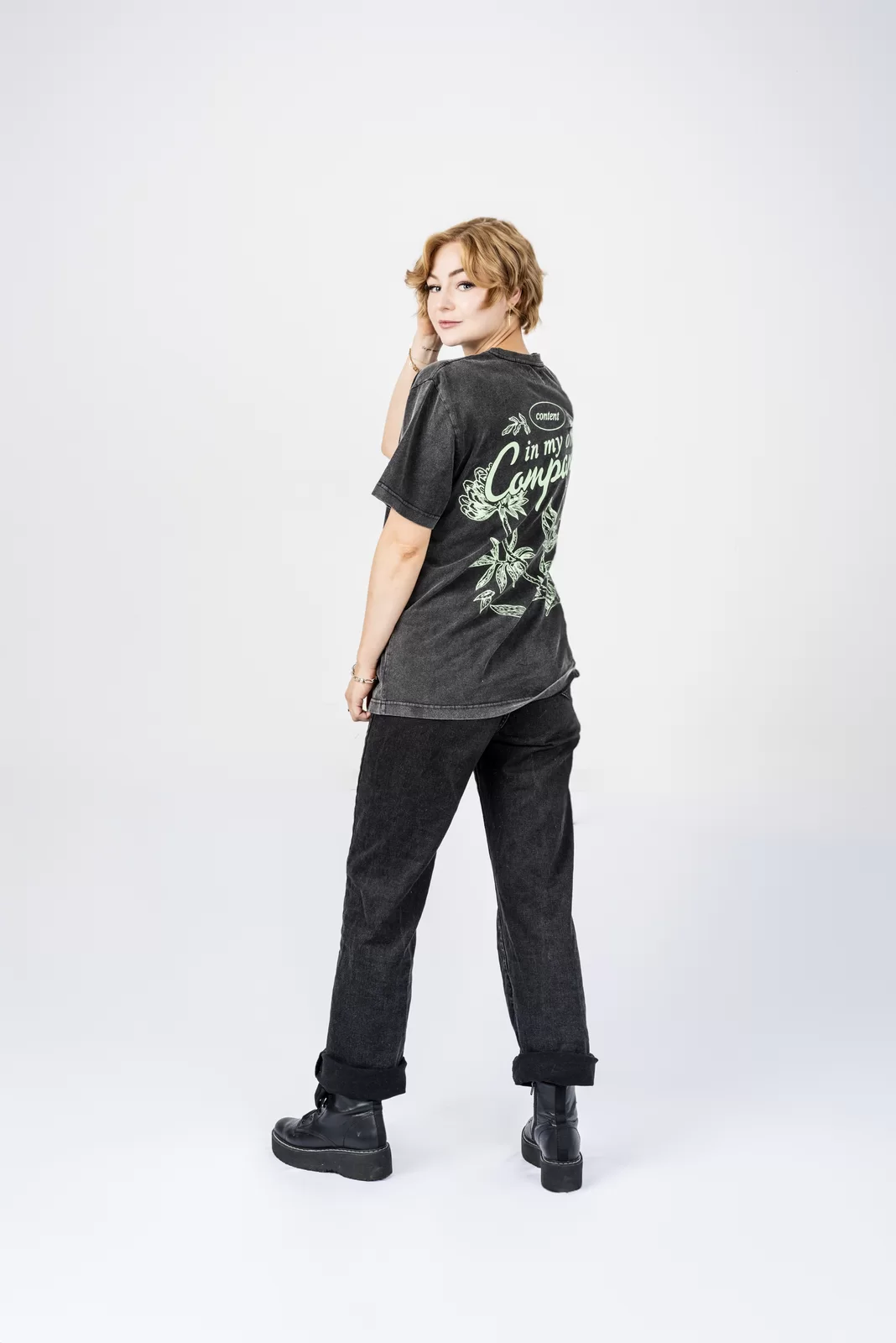Creator branding portrait of Kall Me Kris posing in a black graphic T-shirt against a white background